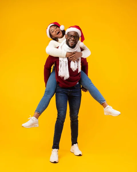 Alegre pareja africana divirtiéndose posando usando sombreros de Santa Claus, estudio — Foto de Stock