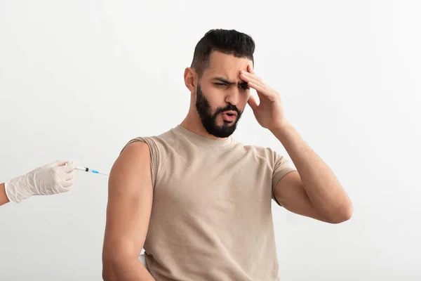 Joven árabe que siente miedo de la vacunación covid, recibir la vacuna contra el coronavirus en el fondo blanco del estudio —  Fotos de Stock