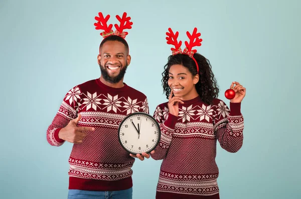 Святкування Нового року. Щаслива афроамериканська пара з годинником, який показує п "ять хвилин до півночі, синє тло. — стокове фото