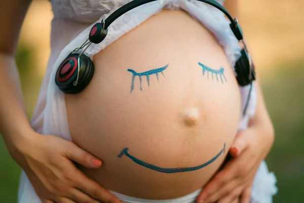 Donna incinta ventre primo piano con sorridente faccia divertente disegno su Immagini Stock Royalty Free