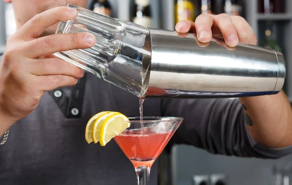 Barman's hands mixing cosmopolitan cocktail