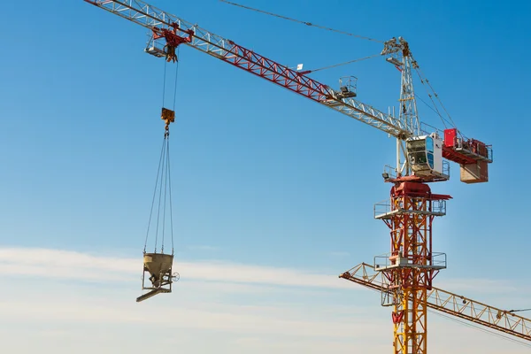 Tower crane lifting up a cement bucket at construction area — Stock Photo, Image