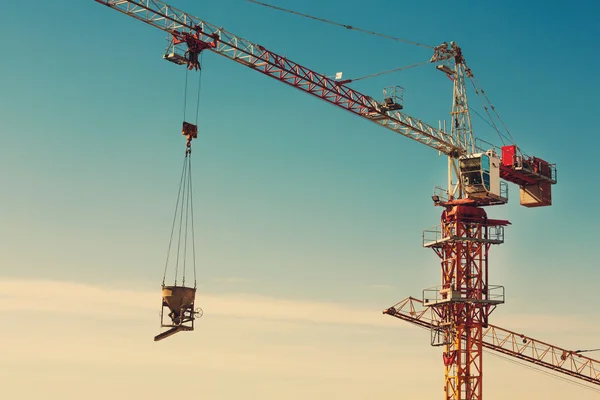 Tower crane lifting up a cement bucket at construction area — Stock Photo, Image