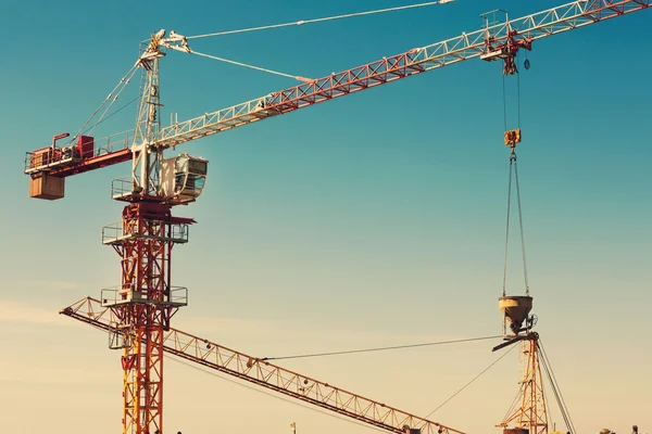 Guindaste torre levantando um balde de cimento na área de construção — Fotografia de Stock