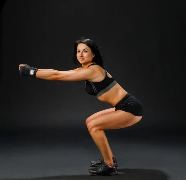 Femme en costume de fitness noir faisant squatting — Photo