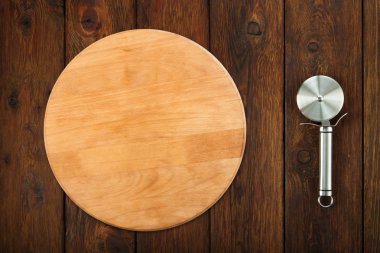 Steel pizza cutter at wooden background