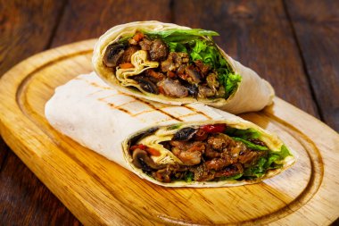 Burritos with pork, mushrooms and vegetables at wooden desk