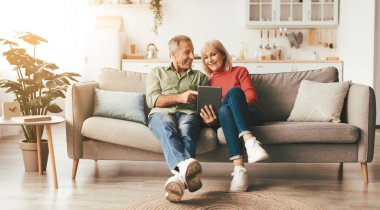 Neşeli Olgun Eşler İnternette Dijital Tablet Tarama Kullanıyor ya da Evdeki Koltukta Birlikte Film İzliyor. Yaşlılar ve Elçiler, Emeklilik Yaşam Tarzı Konsepti