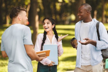 Teneffüste konuşan, kampüste yürüyen, elinde kitap tutan, gülen ve boş alan olan mutlu uluslararası öğrenci arkadaşları. Üniversite hayatı