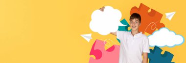 Bir çocuk, beyaz konuşma baloncukları tutarken gülümseyen parlak sarı bir arkaplan karşısında duruyor. Etrafını saran renkli yapboz parçaları eğlenceli bir okul ortamı yaratıyor..