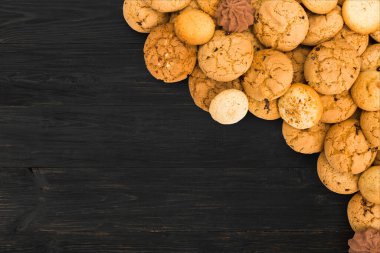 Tanımlama bilgileri arka plan. Siyah rustik ahşap arka plan kopya alanı ile tatlı çikolata bisküvi yığın. Yulaf ezmesi, çikolatam damla ve diğer tatlılar. Besi tatlı çay ahşap masa en iyi görünüm için