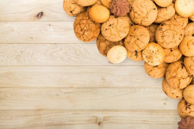 Cookies and sweet biscuits at natural wood, background with copy space. Oatmeal and chocolate drops border, dessert for tea.