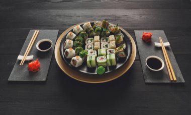 Japon restoranı, suşi roll plakalı rustik ahşap arka plan yeme. İki kişilik yemek çubukları, zencefil, soya, wasabi ile ayarla.