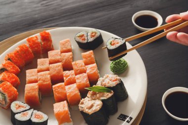 Rulo suşi Japon lokantasında yemek, yemek çubukları closeup ile el. Erkek yemek vardır