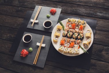Japon Gıda Restoran, california rulo ve suşi tabağı. Yemek çubukları ve siyah arka plan üzerine soya sosu ile ayarla
