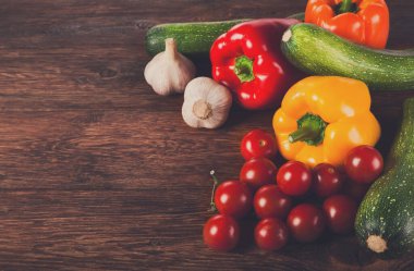 Menü veya tarifi için kahverengi ahşap zemin üzerinde taze organik lezzetli sebze yığını. Ahşap masa üzerinde sağlıklı doğal gıda. Parlak biber ve görünümünün üst pişirme diğer maddeler