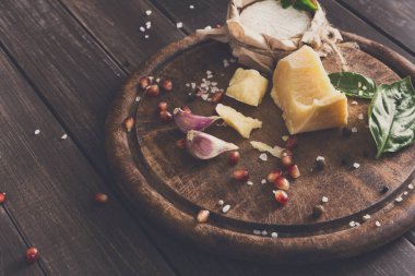 Peynir delikatessen rustik ahşap tepside. Sarımsak, domates ve fesleğen ile dekore edilmiş parmesan, camembert ve brie kesim ile ahşap masa