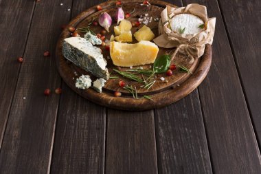 Peynir delikatessen rustik ahşap, kopya alanı üzerine. Mavi peynir rokfor, parmesan, camembert ve brie kesim sarımsak, nar ve fesleğen, Fransız yemekleri malzemeler ile dekore edilmiş