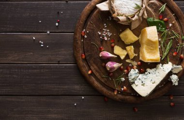 Rustik ahşap üzerine peynir delikatessen üstten görünüm. Ahşap masa mavi peynir ile yuvarlak rokfor, parmesan, camembert ve brie kesim dekore sarımsak, nar ve fesleğen, Fransız yemekleri malzemeler ile