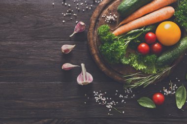 Resepsiyon taze organik sebze ve yeşillik üzerinde tahta arka plan ile. Rustik ahşap masa kopya alanı ile sağlıklı doğal gıda bereket. Üstten Görünüm, yumuşak tonlama malzemeler pişirme