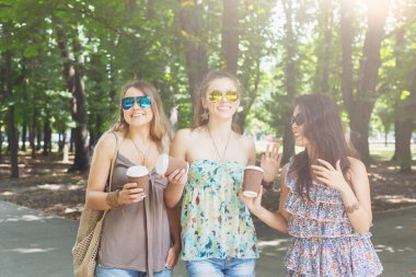Şehirde yaz. Güneş gözlüklü mutlu bayan arkadaşlar, dışarıda eğleniyorlar. Çekici genç kadınlar kahve içer.