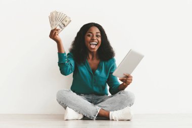 Zengin Afro-Amerikan milenyum bayanı online kumar oynuyor, hisse senedi ticareti yapıyor, modern dijital tablet ve para tutuyor, beyaz stüdyo geçmişi, kopyalama alanı. Borç, piyango, ticaret konsepti