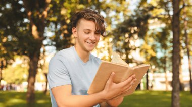 Eğitim konsepti. Genç öğrenci dışarıda kitap okuyor ve sınavlara hazırlanıyor, üniversite kampüsünün bahçesinde öğreniyor, bankta oturuyor. Üniversiteye, üniversite sonrası karantinaya alınma