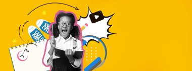 Gözlüklü neşeli bir çocuk etrafı renkli okul malzemeleriyle çevriliyken bir kitap tutuyor..