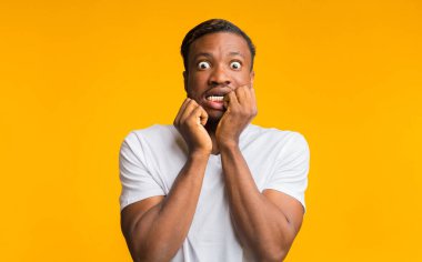 Omg. Korkak Afrikalı Amerikalı Adam, kameraya bakıyor. Sarı arka planda, dokunaklı yüz pozu veriyor. Stüdyo Çekimi