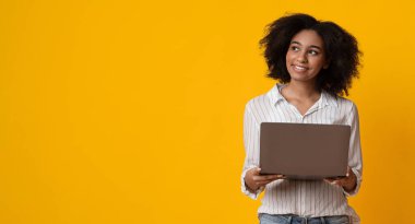 İş Fırsatları İnternet 'te. Dizüstü bilgisayarlı dalgın Afrikalı Amerikalı kadın sarı arka planda boş alana sahip Panorama 'ya bakıyor.