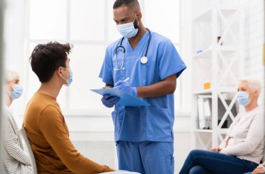 Coronavirus Tıbbi Geçmişi. Afro-Amerikalı doktor, Asyalı hasta adamla hastanenin bekleme odasındaki hastalık belirtileri hakkında konuşuyor. Corona Virüsü, grip konsepti. Boş Alan