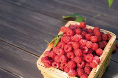 Hasır sepet ahududu closeup ahşap masa arka plan üzerinde dolu. Yaz berry hasat, parlama efekti