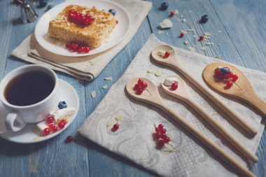 Pasta pasta ve meyveler - yabanmersini, frenk üzümü ve bluberries. Mavi rustik ahşap masa, pasta tatlı etnik porselen tabak, çay ve kahve Kupası'nda, güzel yemekler servis.
