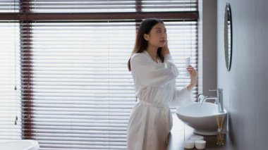 Genç bir kadın banyoda şımartma alıştırması yapıyor. Huzurlu ve rahatlatıcı bir atmosferin tadını çıkarırken cilt bakımı yapıyor. Mekan, huzurlu bir yaşam tarzı ve kişisel bakım alışkanlıklarını yansıtıyor..