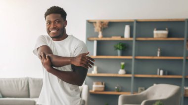 Isınma Kavramı. Ev eğitiminden önce kollarını esneten, oturma odasında kameraya bakan, gülümseyen adam ve kadın vücut uzunluğuyla birlikte egzersiz yapan mutlu siyahi bir çiftin portresi.