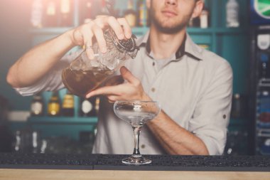 Genç yakışıklı barmen cam içine iç dökme alkol kokteyl içki bar. Hizmet Sektörü Meslekleri.