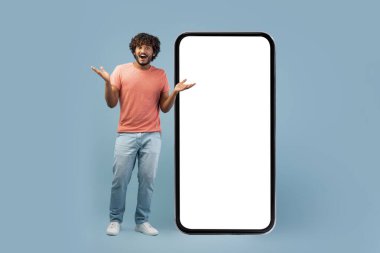Cool East Man beyaz ekranlı büyük bir akıllı telefonun yanında dururken şaşırmış bir yüz ifadesi sergiliyor. Coşkulu bir şekilde el kol hareketi yapıyor, harika bir online fırsat sunuyor..