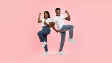 Genç siyahi erkek ve kadın heyecanlarını sıkılmış yumruklarını zıplayıp sallayarak ifade ederler. Mutlu ve sevinçli görünüyorlar. Pembe bir arka planda zaferi kutluyorlar..