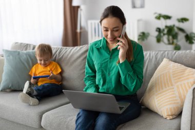 Sıcak bir oturma odasında, bir anne dizüstü bilgisayarı üzerinde çalışırken bir telefon görüşmesi yapar. Küçük oğlu bir aletle oynuyor. İkisi de sakince eğleniyor..