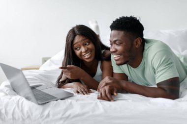 İki arkadaş bir yatakta yatıp dizüstü bilgisayar izlerken kahkaha ve neşeyi paylaşıyorlar. Rahat ve rahat odalarında eğlenceli bir aktiviteyle meşguller..