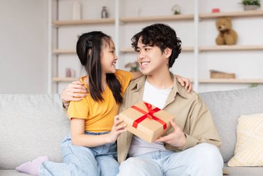 Neşeli bir baba, gülümseyen kızına güzel bir hediye verir. Oturma odasında güzel bir an yaratır. Sevgi ve mutlulukla dolu yakın bir bağları var..