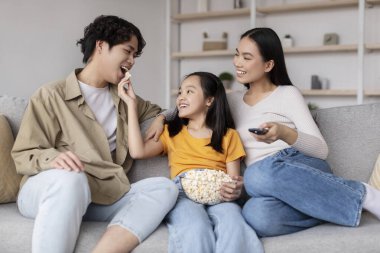 Neşeli bir aile oturma odasında birlikte kaliteli zaman geçirir. Patlamış mısırlarını ve gülümsemelerini paylaştıkları bir film gecesinden hoşlanırlar. Ortam sıcak ve sevgi dolu..