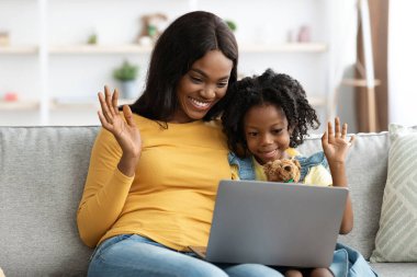 Bir anne ve kızı mutlu bir şekilde dizüstü bilgisayarlarına el sallıyor, keyifli bir anı paylaşıyorlar. Parlak, davetkar bir yaşam alanında rahat bir kanepede otururlar. Aile veya arkadaşlarla iletişim kurarlar..