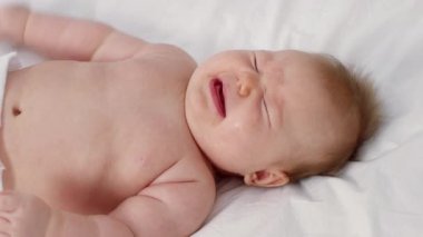 Yeni doğmuş şirin bir bebek evdeki yumuşak bir battaniyeye uzanmış aile tarafından bakılırken rahatsız edici ifadeler sergiliyor. Atmosfer sıcaklık ve sevgiyle dolu..