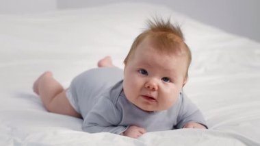 Neşeli bir bebek evdeki yumuşak bir yüzeye uzanmış merakla çevreyi keşfediyor. Sıcak atmosfer aile sevgisi ve ilgisinin bağını vurguluyor, bunu iç açıcı kılıyor..