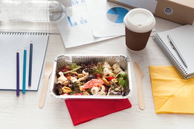 Sağlıklı bir iş öğle ofis, kahve almak uzakta ve Beyaz ahşap masa üzerine folyo kapta sebze salatası. Mola zamanı snack