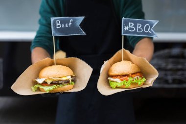 Sokak fast food festivali, açık havada barbekü yapan hamburgerler. Izgara Amerikan bbq yemekleri, şeflerin ellerinde el işi kağıt ve metin etiketleri.