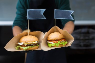 Sokak fast food festivali, açık havada barbekü yapan hamburgerler. Izgara Amerikan bbq yemekleri, şeflerin ellerinde el işi kağıt ve metin etiketleri.