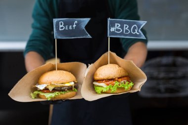 Sokak fast food festivali, açık havada barbekü yapan hamburgerler. Izgara Amerikan bbq yemekleri, şeflerin ellerinde el işi kağıt ve metin etiketleri.