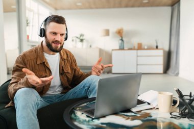 Kulaklık takan genç bir adam aktif olarak sanal bir toplantıya katılıyor..